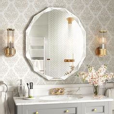 a bathroom with a mirror, sink and two lights on the wall above it is decorated in white and gold