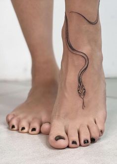 a woman's foot with a snake tattoo on the top of her left leg