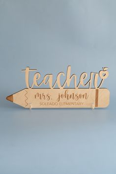 a wooden teacher's name sign with a pencil on it that says, teachers