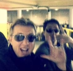 two men taking pictures with their cell phones in a parking garage while one man holds his hand up to the camera