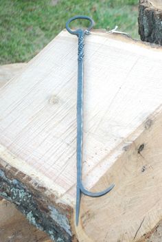 a piece of wood with a metal hook on it's end sitting next to a tree stump