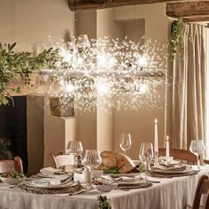 a dining room table is set with white plates and silverware, surrounded by greenery