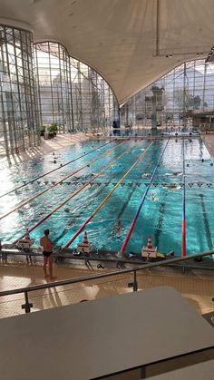 an indoor swimming pool with multiple lanes and people in the water looking out at it