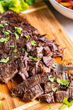 a cutting board topped with sliced up meat and garnished with cilantro