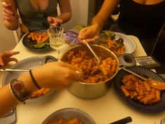 several people sitting at a table with plates and bowls of food in front of them