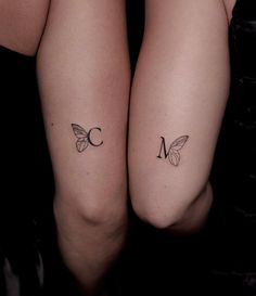 two women with matching tattoos on their legs, both showing the letter m and butterfly