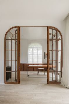 an open door leading to a dining room with wooden furniture and white drapes on the windows