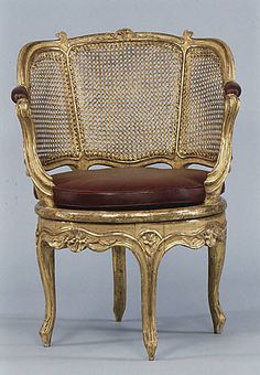 an antique chair with a leather seat and back cushion is shown in this image, it appears to be gold