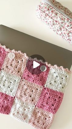 a pink and white crocheted purse sitting on top of a laptop computer next to a wallet