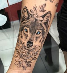 a woman's arm with a wolf and flowers tattoo on her left forearm, which has blue eyes