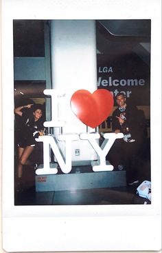 two people standing next to each other in front of a sign that says i love new york