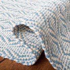 a blue and white blanket laying on top of a wooden floor