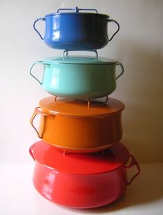 four pots stacked on top of each other in different colors and sizes, with lids