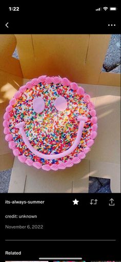 a pink cake with sprinkles on it and a smiley face in the middle