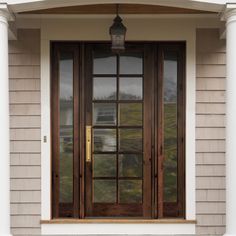 the front door of a house with two windows and a light fixture on the side