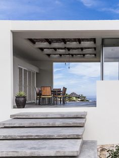 an outdoor dining area with steps leading to the patio and ocean in the back ground