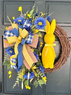 a wreath decorated with blue and yellow flowers, an easter bunny ornament on the front door