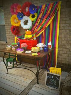 a table topped with cakes and cupcakes on top of a wooden floor next to a brick wall