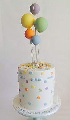 a birthday cake decorated with balloons and confetti