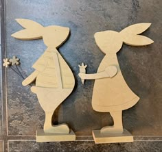 two wooden cutouts of rabbits holding hands