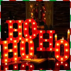 lighted letters spelling the word ho ho in front of a christmas tree with lights on it