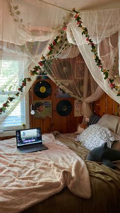 a laptop computer sitting on top of a bed covered in white drapes and curtains