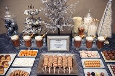 a table topped with lots of food and desserts next to a christmas tree in the background