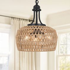 a chandelier hanging from the ceiling in a room with curtains and windows behind it