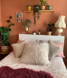 a bed with two pillows and some plants on the headboard in front of it