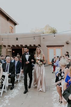 a bride and groom walking down the aisle after their wedding ceremony at an adobe - style venue