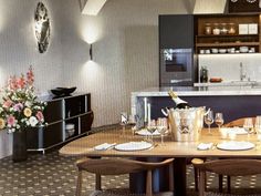 a dining room table with wine glasses on it and flowers in vases at the end