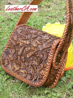 a brown purse sitting on top of a grass covered field next to a yellow object