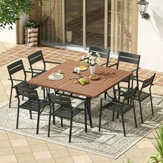 an outdoor dining table and chairs set up on a patio with potted plants in the background