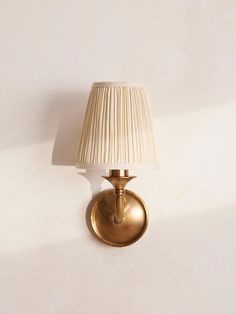 a gold wall light with a white shade on the lamp is shown in an empty room