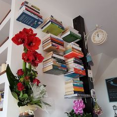 flowers and books are arranged on the wall next to a shelf with many books in it