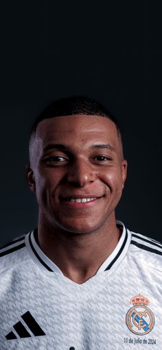 a man in a soccer uniform smiling for the camera with his head tilted to the side