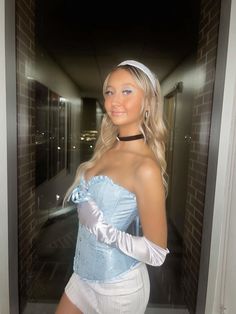 a woman in a blue corset and white skirt posing for the camera with her hands on her hips