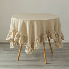 a round table with ruffled edges and wooden legs in front of a white wall