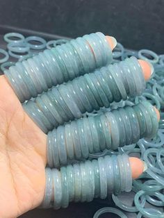 a hand holding some blue spirals on top of a black table with rings around it