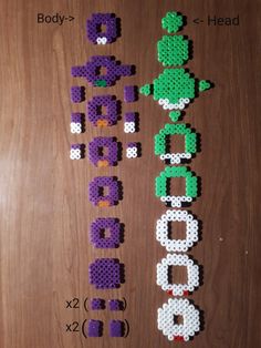 the letters made out of perler beads are displayed on a wooden surface, with each letter in different colors