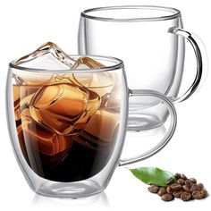 two glass mugs filled with liquid and coffee beans next to each other on a white background