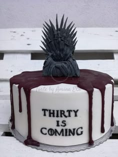 a game of throne cake sitting on top of a white bench