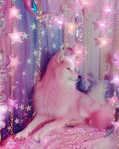 a white dog sitting on top of a bed covered in pink and purple stars next to balloons