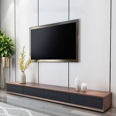 a flat screen tv mounted on the wall next to a vase with flowers in it