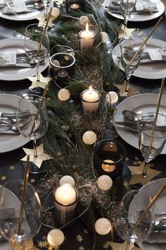 the table is set with candles, plates and silverware for an elegant christmas dinner