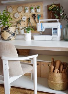 a sewing machine sitting on top of a white desk next to a chair and potted plant