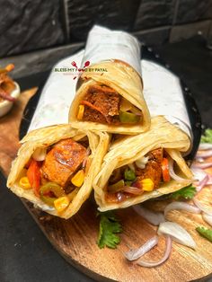 three burritos with meat and vegetables on a cutting board