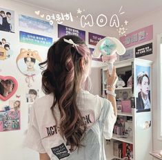 a girl is standing in front of a wall with posters on it and holding a hair brush