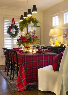 a dining room table decorated for christmas with wreaths and candles