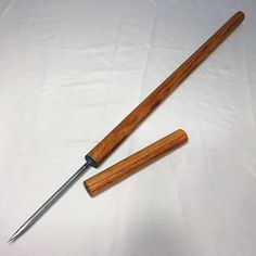 two wooden handled knives on a white tablecloth with a knife stuck in the handle